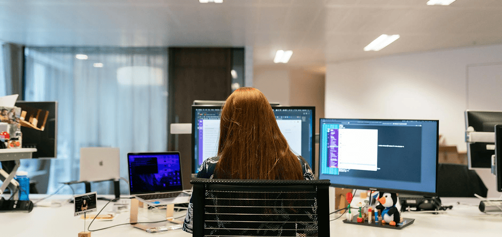 A woman sitting in front of several computer screens.